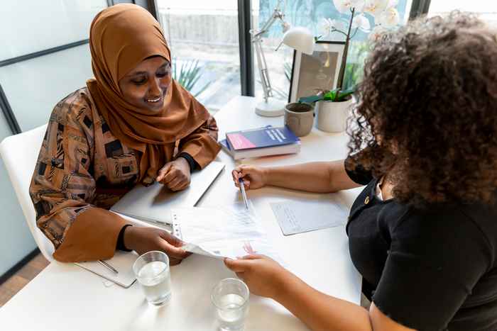 Juridisch adviseur van de Vrouwenrechtswinkel Amsterdam helpt een client terwijl ze aan tafel zitten.