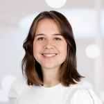 Portret van docent, lachend in camera met wit shirt en lichte achtergrond